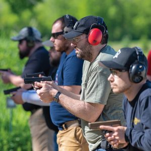 Students on the firing line holding defensive pistols awaiting the "fire" command from the instructor. 