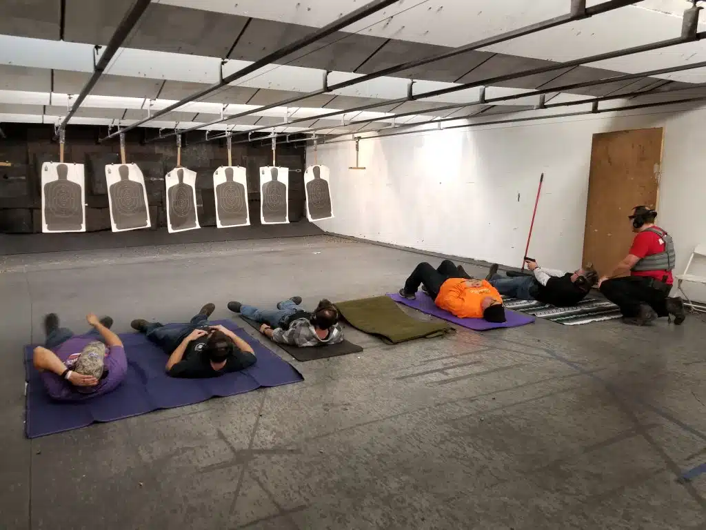 Students in laying shooting position about to draw and fire their pistols.