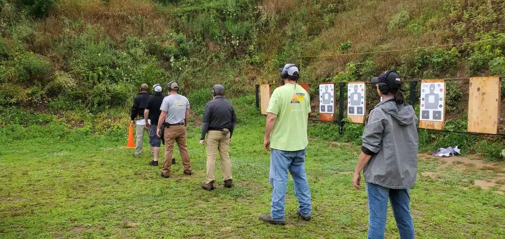 Students on an outdoor range, about to turn and draw their pistols in a Defensive Pistol class.