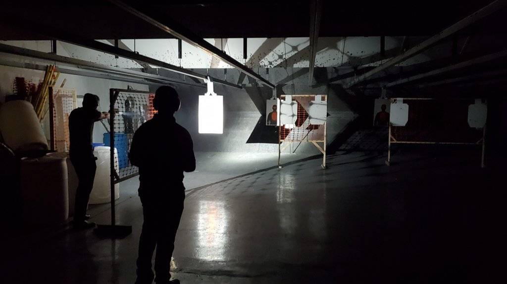 Image of low-light pistol shooting class with student and instructor. 