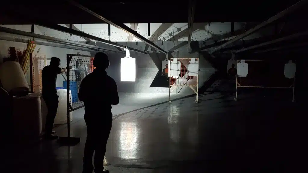 Image of low-light pistol shooting class with student and instructor.